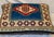 A handwoven kilim textile accent pillow featuring a bold geometric medallion within a richly patterned border, executed in...