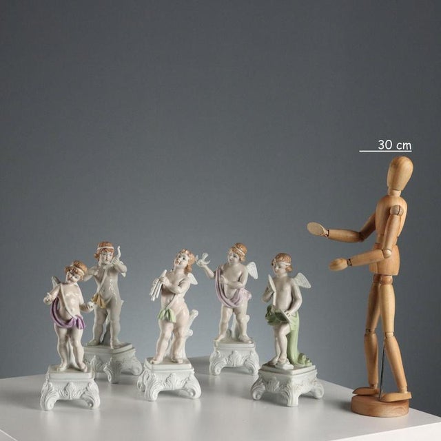 Group of five polychrome porcelain figurines depicting winged cherubs. Mark under the base. This piece is attributed to...