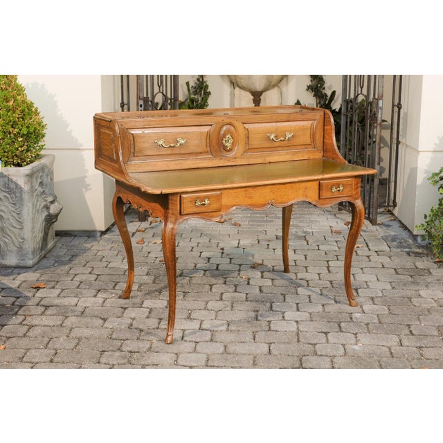 A French Louis XV style walnut desk from the early 19th century, with lifting panel, green leather writing surface and...