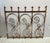 This vintage ornate wrought iron gate features decorative scrollwork and pointed finials. Significant rust and gray paint...