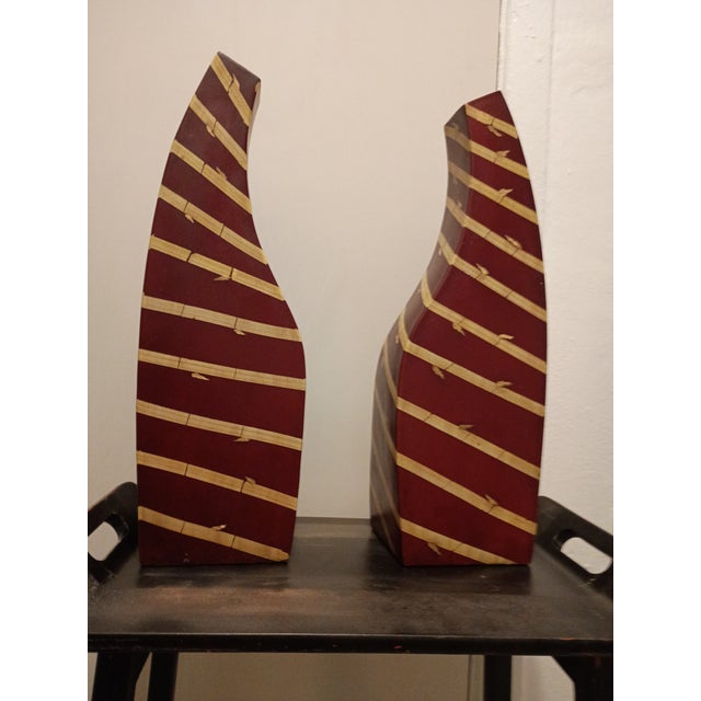 A striking pair of hand-carved sculptural totems crafted from bamboo with a deep oxblood red finish. These abstract,...