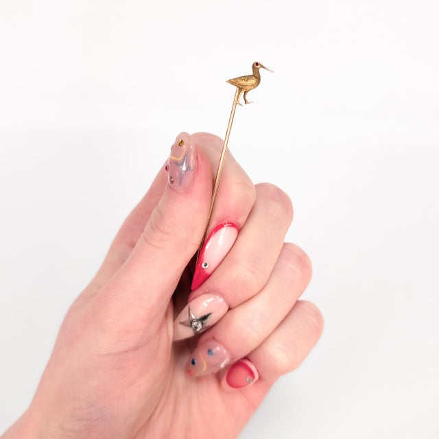 A fine vintage gold stickpin. In 14 karat yellow gold with ruby eyes. In the form of an sand piper. Marked to the reverse...