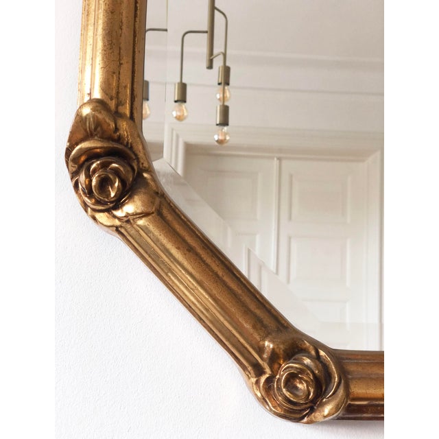A giltwood beveled mirror with golden rose accents, inspired by Rococo style and made in Italy around 1960. Object: Mirror...
