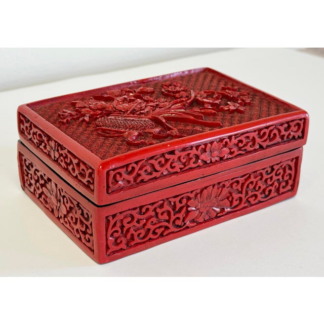 Stunning vintage hand-carved lidded red cinnabar lacquer trinket box with detailed flower arrangement motif. Exquisite...