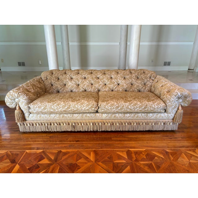 An exquisite custom tufted sofa with damask upholstery with a double bullion and tassel fringe and large tassels on the...