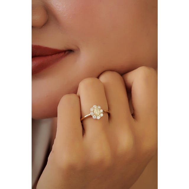 This cluster engagement ring features a 0.79 carats natural diamond set in 14K yellow gold. The center oval-cut diamond...