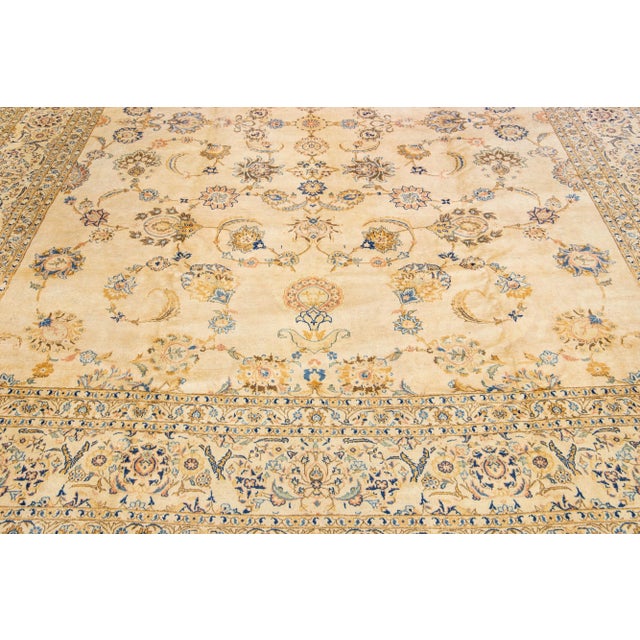 Beautiful Antique Kashan hand-knotted wool rug with a beige color field. This Persian rug has blue, golden, and brown...