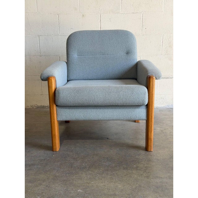 This comfortable lounge chair features a robust wooden frame with cushioned armrests and a gently angled backrest. The...