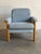 This comfortable lounge chair features a robust wooden frame with cushioned armrests and a gently angled backrest. The...