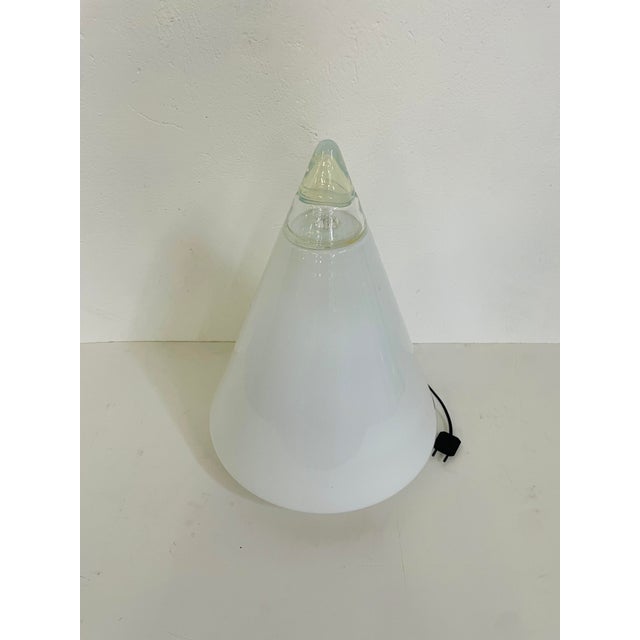 Rio model table lamp, with a round base in opaline white Murano glass. The structure is conical, the tip of the lamp is...