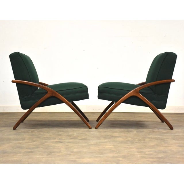 A pair of mid century modern walnut colored lounge chairs newly reupholstered in green. Made from solid birch....