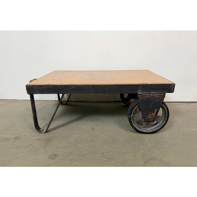 Former pallet truck from a factory now serves as a coffee table. It features a black iron construction with two original...