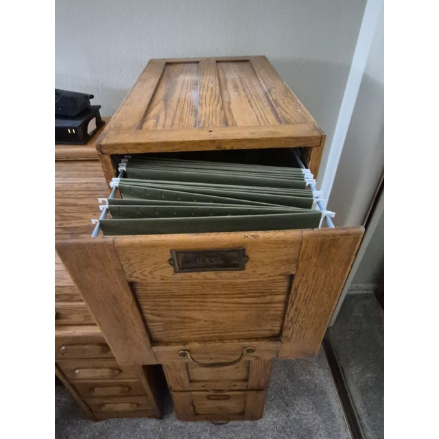 This is a vintage or antique 4-drawer vertical filing cabinet made of solid oak, featuring raised-panel drawer fronts,...