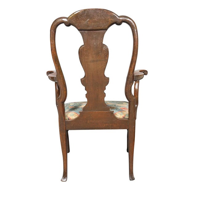 George I Walnut Armchair with arched and scroll carved back, vasi-form splat with banded edge. Needlepoint drop in seat....