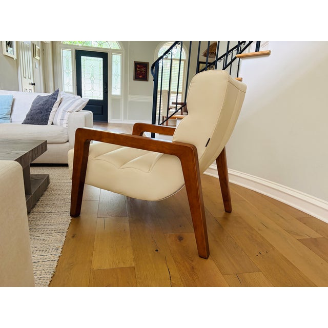 Modern contemporary lounge chair by Opulence Home featuring a sculptural wood frame with cream upholstered cushions. This...