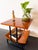 This mid-century modern magazine table in wood and black metal features a graphic, architectural design with a square top...