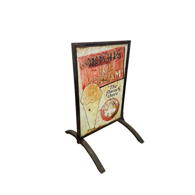 A rare and authentic two-sided painted metal advertising sign for Hood’s Ice Cream, displayed in its original iron...
