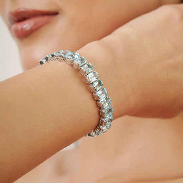 This elegant tennis bracelet is crafted in 925 sterling silver and set with 33 natural Blue Topaz gemstones totaling an...