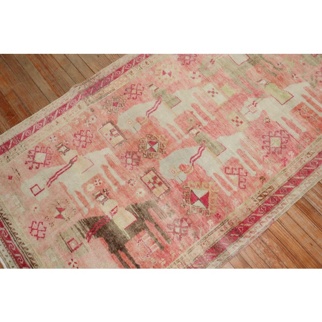 A russian Karabagh from the 2nd quarter of the 20th century with a pictorial caravan motif in pink Measures: 3'10'' x 8'2''.