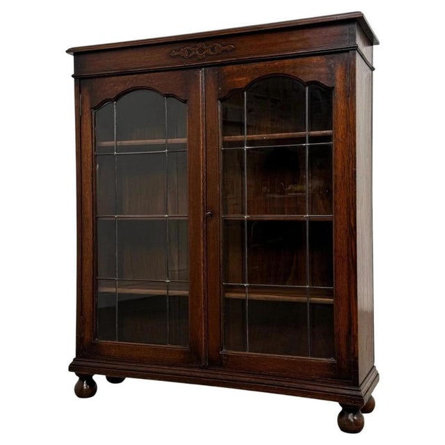 A handsome early 20th-century English display cabinet, finely crafted from oak and distinguished by its elegant glazed...
