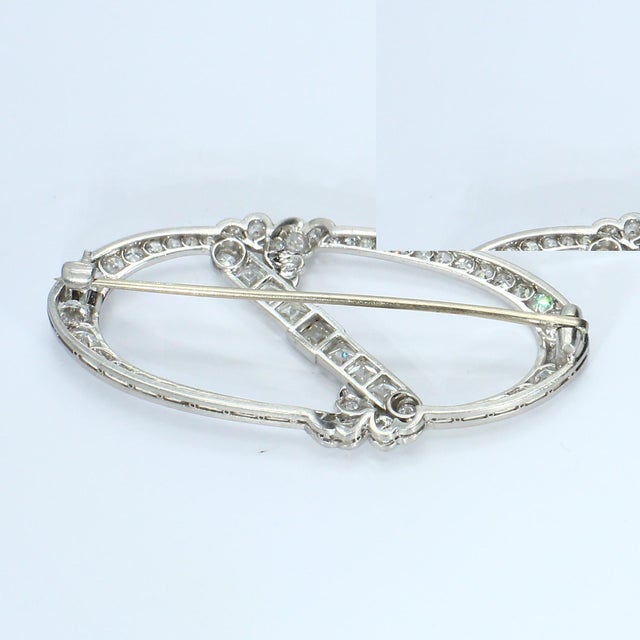 This brooch features an elegant oval design adorned with a series of white diamonds. The central bar is set with French-...