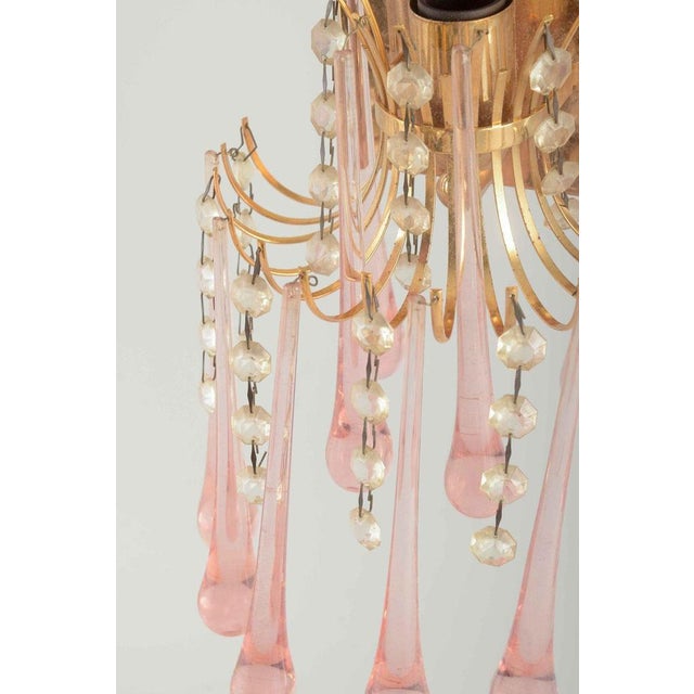 Murano. A pair of elegant wall lamps in brass with suspended teardrop-shaped prisms in pink murano glass and clear glass...