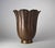 An Arts and Crafts period fluted floriform vase in copper with a flaring rim and original dark brown patina resting on a...
