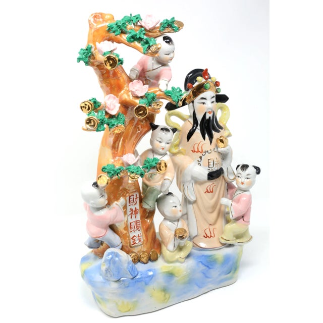 A hand-sculpted and painted figure of Chinese prosperity god, Lu, surrounded by children climbing a tree with gold coins....
