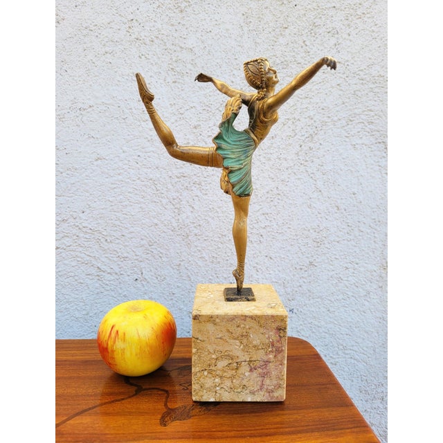 Elegant bronze ballerina with a multicolored patina, poised on pointe, mounted on a marble base. This sculpture is signed...