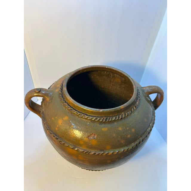 A substantial and sculptural hand-thrown studio pottery vessel featuring a classic double-handled form with applied rope-...