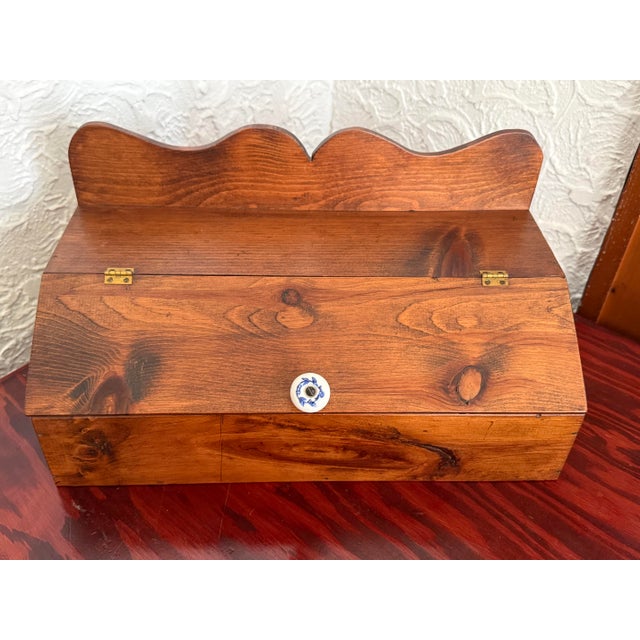 Knotty pine box with a hinged slanted lid and a scalloped backsplash. The lid opens on small brass hinges and has a white...