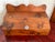 Knotty pine box with a hinged slanted lid and a scalloped backsplash. The lid opens on small brass hinges and has a white...