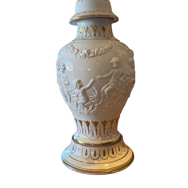 A fine pair of neoclassical porcelain table lamps featuring urn-form bases adorned with raised relief scenes of...