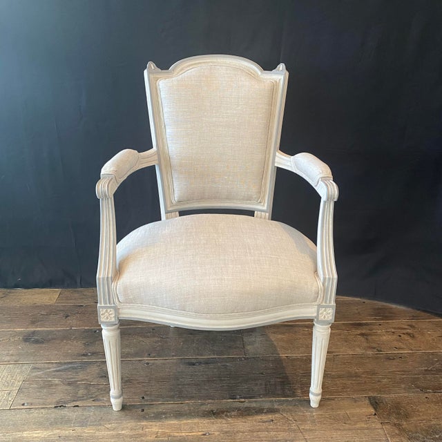 An elegant pair of antique French Louis XVI fauteuils, beautifully crafted with gracefully shaped shield backs, fluted...
