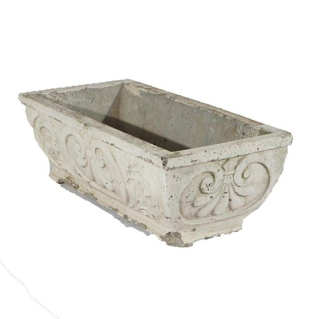 A long garden or patio planter crafted from cast hardstone, featuring intricate scroll work in relief. This piece is from...