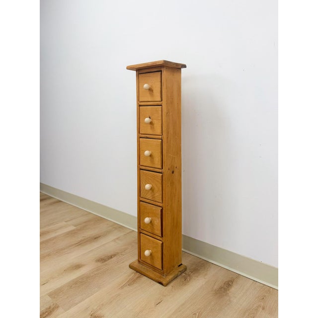 This charming vintage pine six drawer narrow vertical apothecary cabinet is a delightful and highly functional artisan...