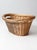 This is a vintage wicker laundry basket. The natural woven basket features inset handles on the sides and a rolled top edge.