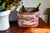 Vintage oval toleware planter with hand-painted sepia-burgundy pastoral scene: a lakeside house, sailboat, rowboat, and...
