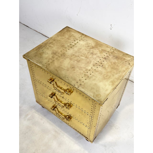 Brass clad three drawer chest with overhanging top and wooden bun feet by Sarreid, circa 1970s.