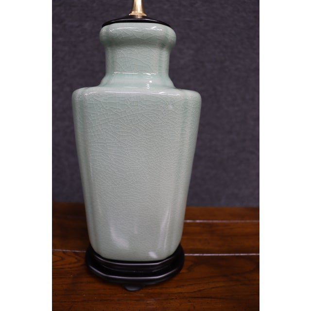 Pair of glazed ceramic table lamps in a soft celadon green finish with classic chinoiserie form. Each lamp sits on a black...