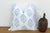 A repeating diamond medallion in soft blue ink covers the full face of this pillow, hand block-printed on ivory linen —...