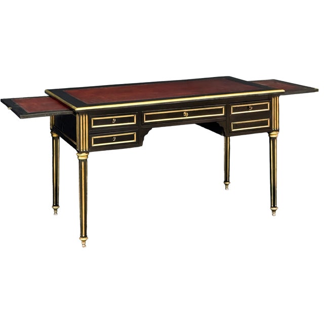 An elegant French writing desk or table of ebonized wood with gilt accents in the Louis XVI style. Featuring a moulded,...