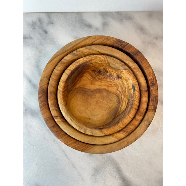 Set of three hand-turned olive wood bowls featuring beautifully figured grain, warm natural tones, and an organic...
