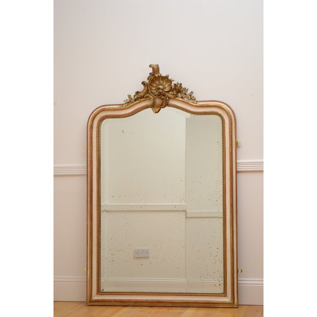 An unusual french 19th-century wall mirror featuring an elegant cream and water-gilded gold leaf frame. The shaped and...