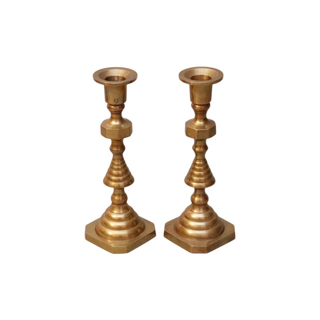 A pair of traditional candlestick holders made of brass. Turned with beehive shaped columns above square bases. Dimensions...