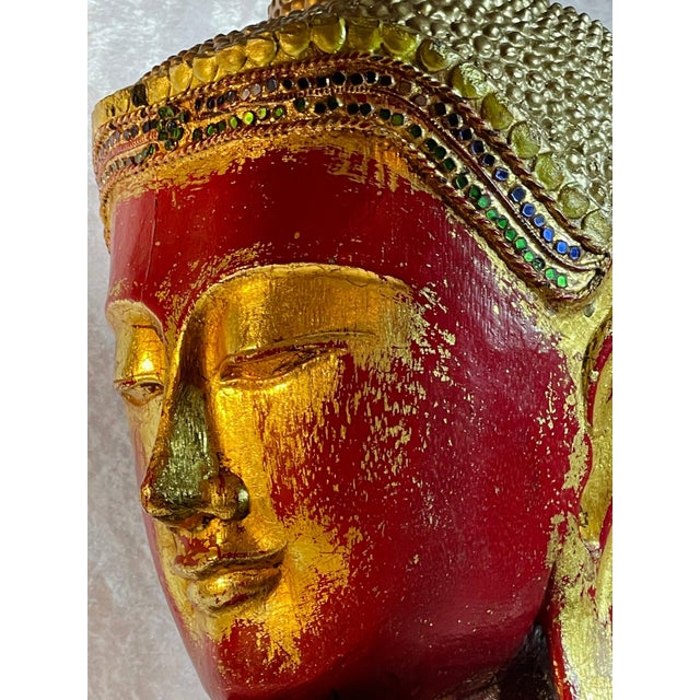 Carved wood Buddha head, early 20th century, with red lacquer showing through gold leaf that handling has worn thin, and a...