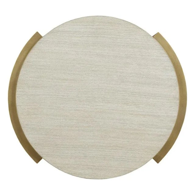 This table features a circular top in quarter sawn ash and elevated by a brass plated stainless steel base with four legs...