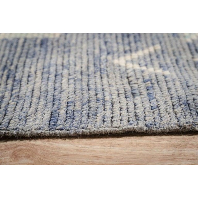 This blue wool rug features a hand knotted pile weave and originates from Pakistan. It reflects the traditional Berber...