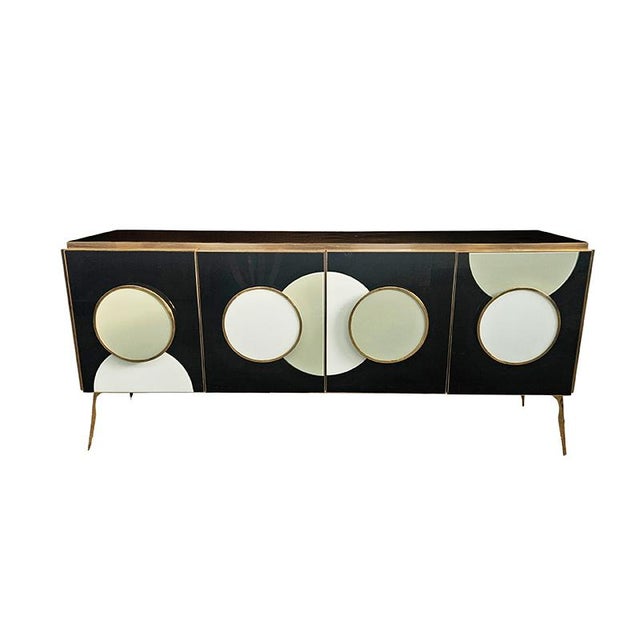 Four-door sideboard with internal shelf, entirely handmade, with a wooden frame covered in black glass. Gilded brass trim...