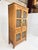 This is a handsome vintage wood cabinet distinguished by woven cane panel doors and elegant carved detailing along the...